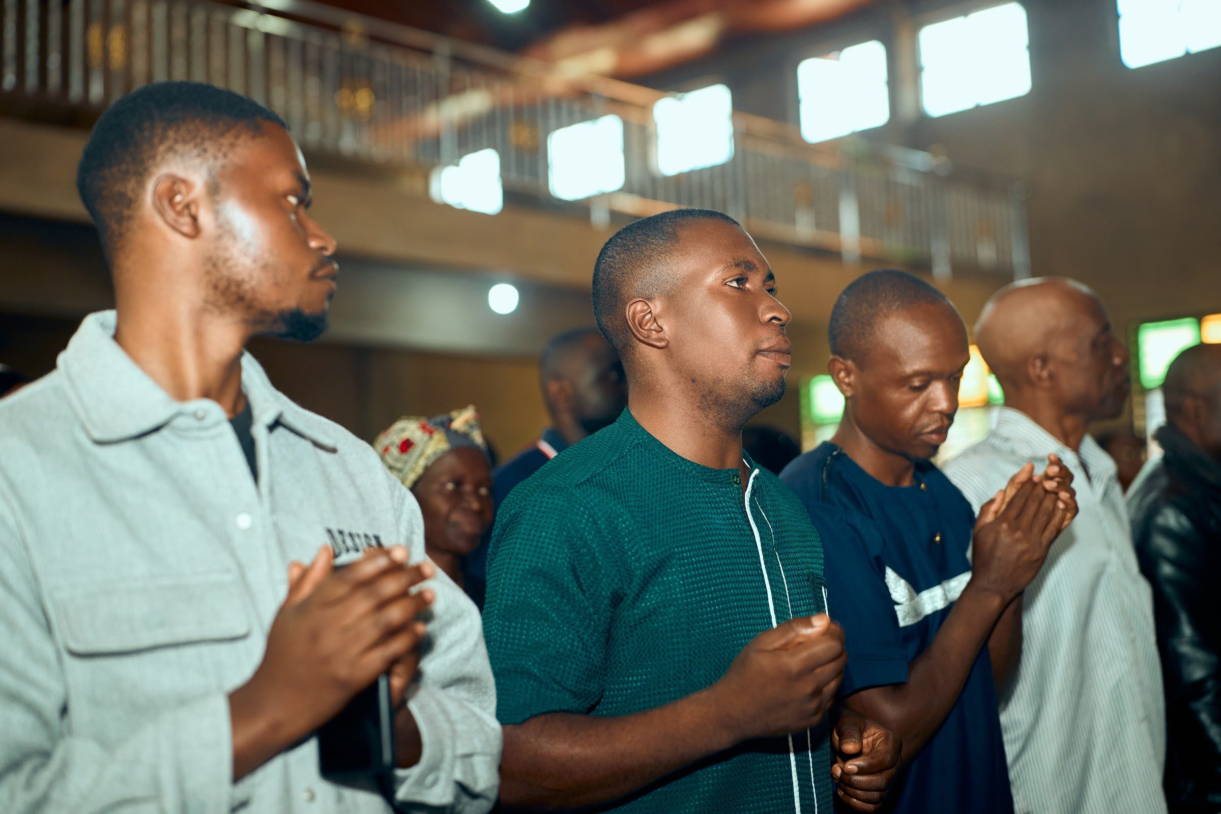 Congregation standing with hands folded in prayer